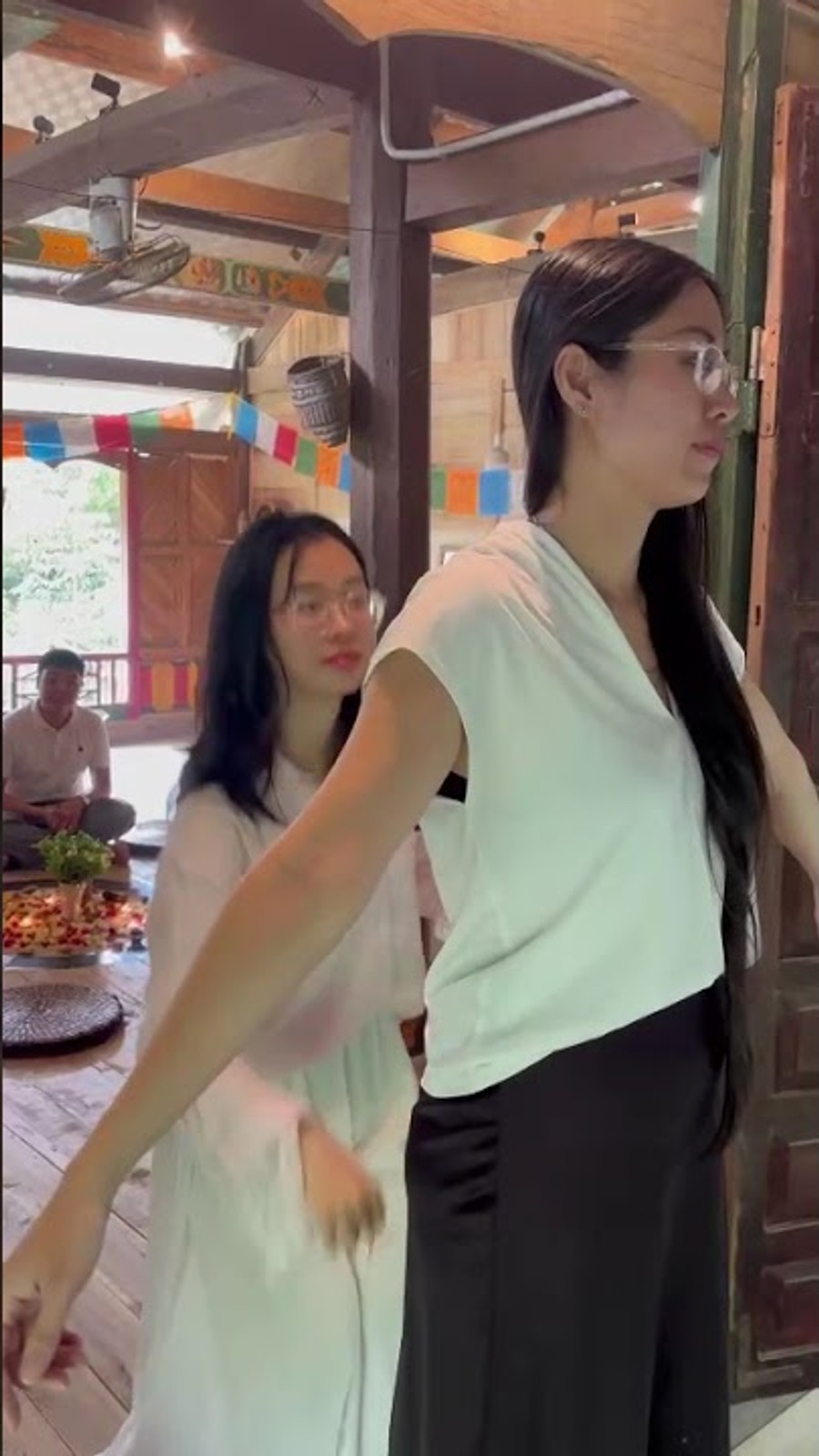 Hai người trò chuyện trong nhà sàn gỗ, cờ Tây Tạng nhiều màu phía sau